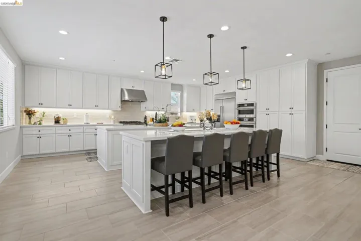 Kitchen featuring an island with sink, a breakfast bar, white cabinets, and stainless steel appliances