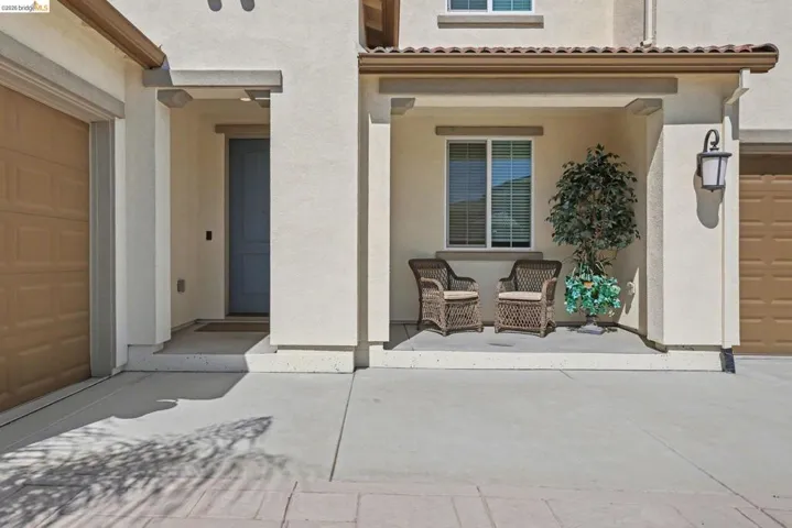 Entrance to property featuring stucco siding, a garage, and a patio