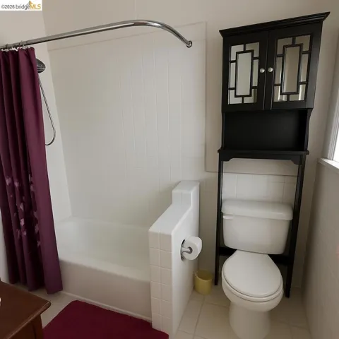 Bathroom with shower / tub combo, tile walls, and light tile patterned flooring