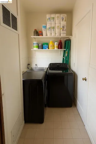 Laundry room with washer and clothes dryer and light tile patterned flooring