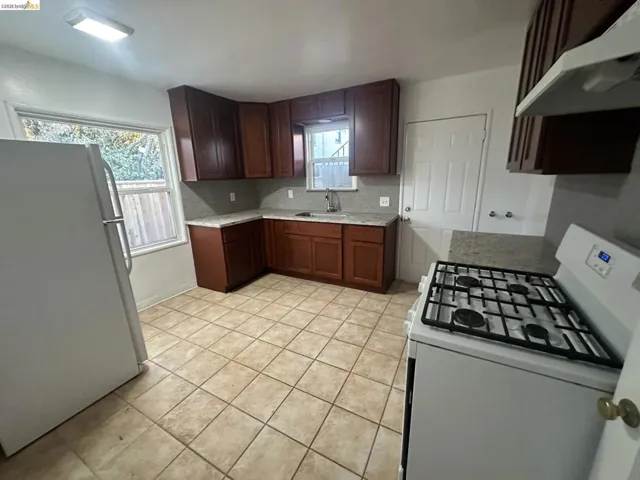 Kitchen with white appliances, decorative backsplash, and light tile patterned floors