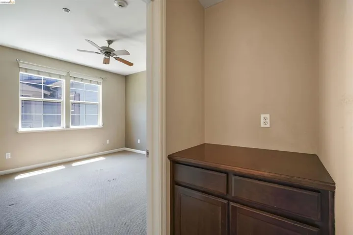 Carpeted spare room with ceiling fan and baseboards