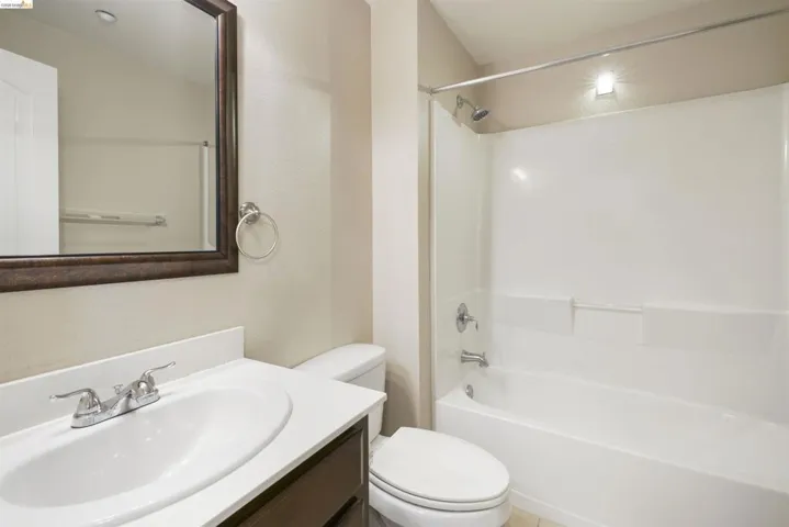 Bathroom with vanity, shower / tub combination, and a textured wall