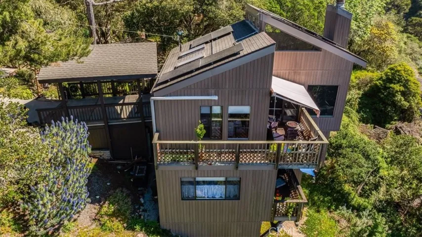 Side view of house from drone showing the carport, top deck and bottom deck.