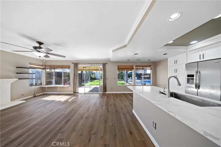 Expansive Great Room Open To The Kitchen With Ceiling Fan And Backyard Views