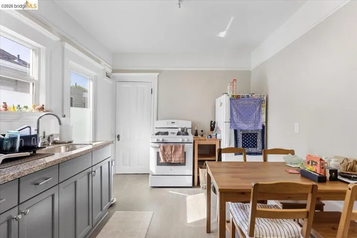 Kitchen with white appliances, gray cabinetry, and light stone counters