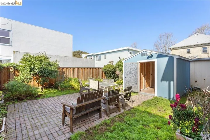 Fenced backyard featuring a patio area, outdoor dining space, and a storage shed