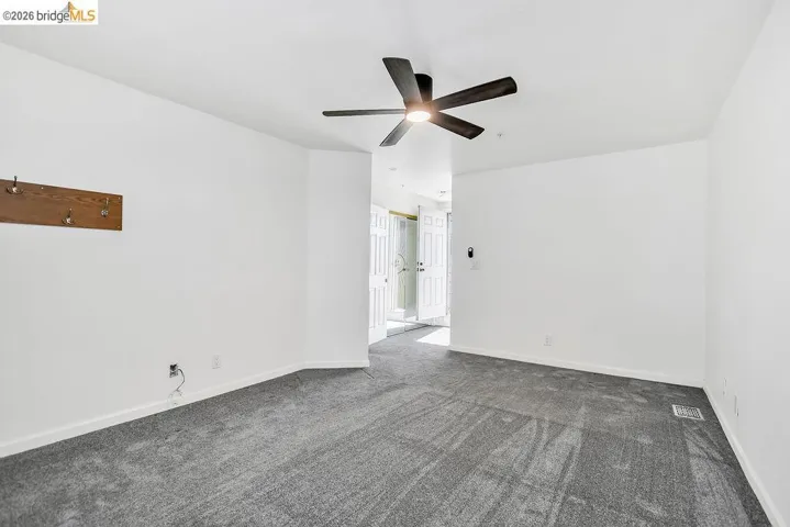 Unfurnished room with dark colored carpet and ceiling fan