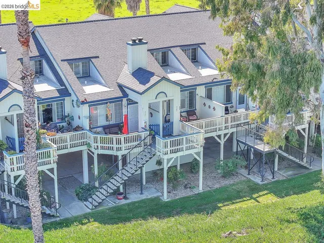 Back of property with a deck, a patio area, a chimney, and a lawn