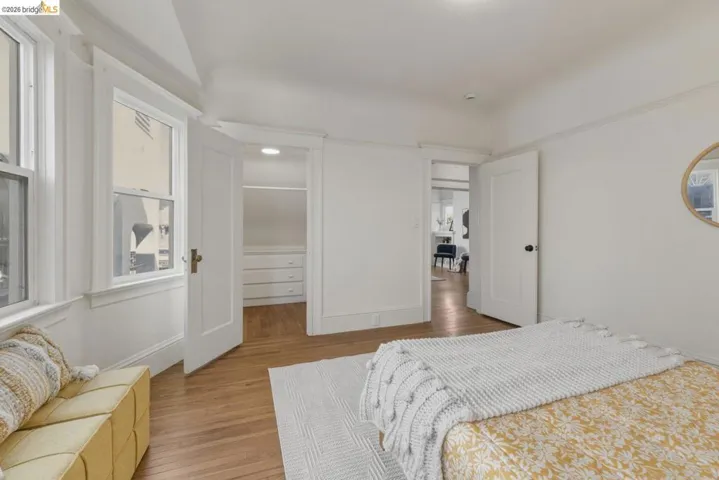 Bedroom with light wood-style flooring, multiple windows, and a walk in closet
