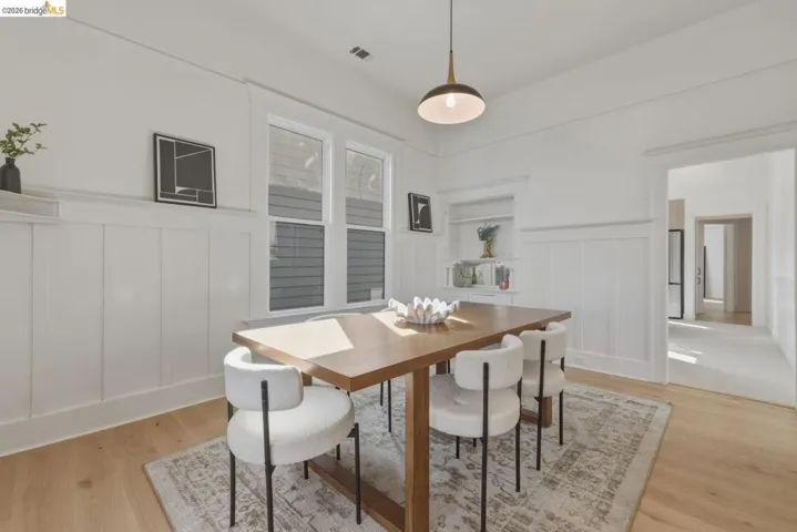 Dining area with a wainscoted wall, a decorative wall, and light wood finished floors