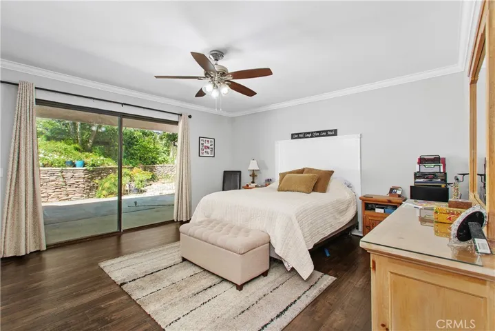 The primary bedroom has a sliding door with access to the back patio. Also, notice the crown molding and lovely flooring.