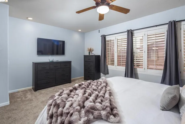 Bedroom with light carpet, ceiling fan, and recessed lighting
