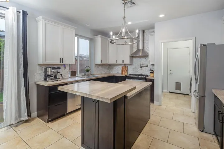 Kitchen featuring stainless steel appliances, a kitchen island, decorative backsplash, wall chimney exhaust hood, and recessed lighting