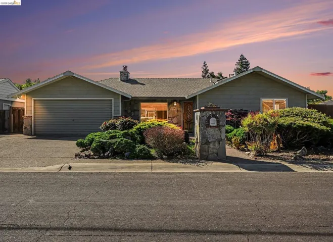 Ranch-style house featuring driveway, a chimney, stone siding, and an attached garage