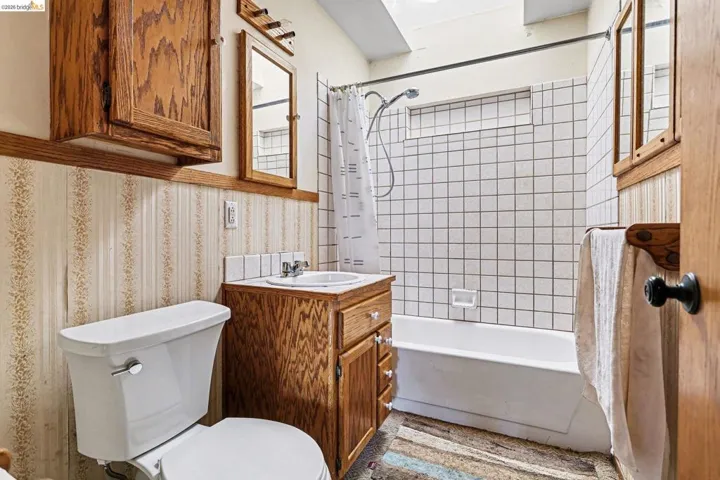 Bathroom featuring shower / bath combination with curtain, vanity, and wallpapered walls