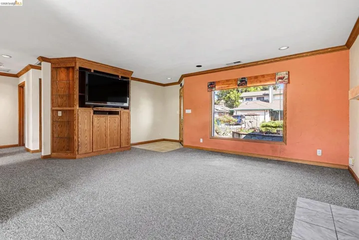 Unfurnished living room with light carpet and ornamental molding