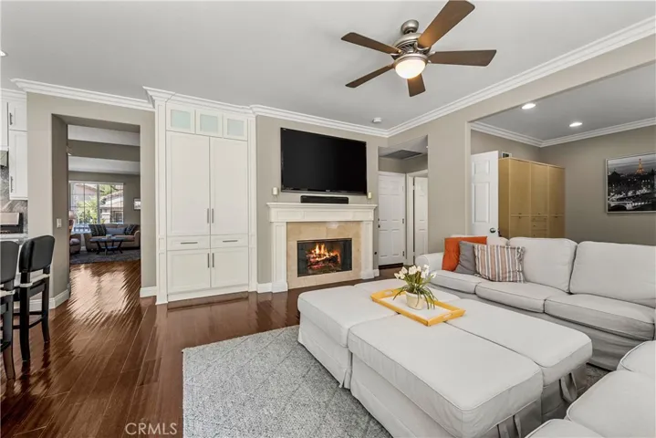 Family room with wood floors, custom cabinetry, crown molding and ceiling fan.Fire has been digitally added to the fireplace