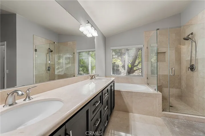Primary bath has been upgraded marble countertops, marble floors, glass enclosed walk-in shower with marble tile floors and walls