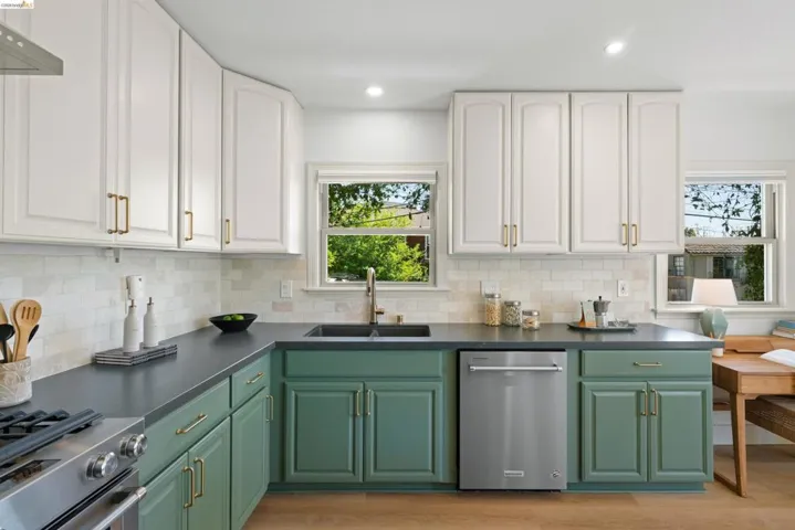 Dual tone kitchen with two tone color scheme, stainless steel appliances, light wood-type flooring, recessed lighting, and backsplash