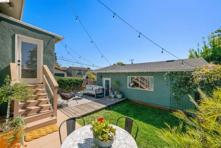 Rear view of house with a wooden deck, stucco siding, outdoor lounge area, a yard, and roof with shingles