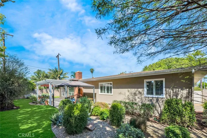 The pathway continues to a wide side yard on the east side of the property and is lined with shrubbery of various species.