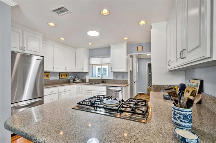 Quartz countertops, white cabinets and stainless appliances in the kitchen. A sky tube and recessed lighting provide a light & bright work space.