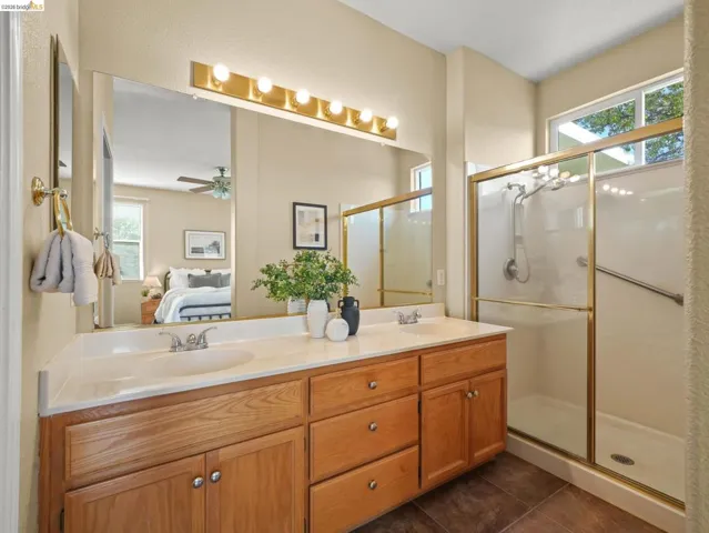 Bathroom featuring ensuite bath, double vanity, plenty of natural light, and a shower stall
