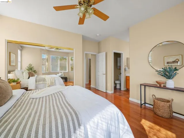 Bedroom featuring wood finished floors, a closet, ceiling fan, and connected bathroom