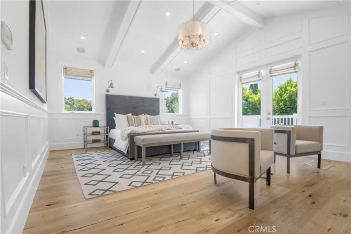 Primary bedroom with vaulted ceiling and balcony