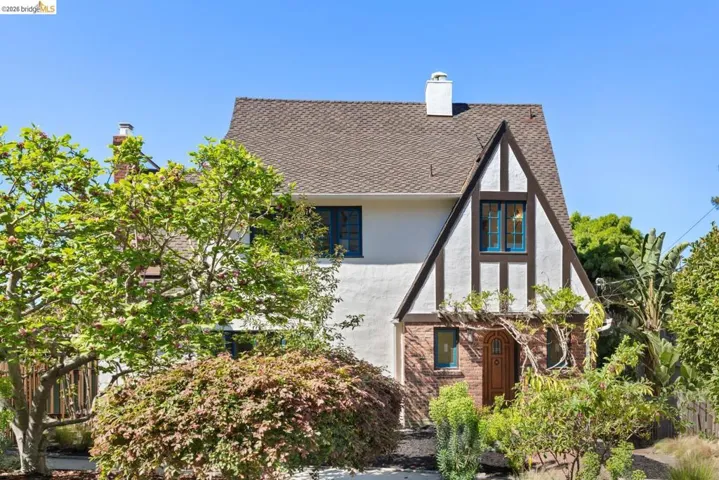 View of front of house featuring a chimney, stucco siding, and a shingled roof