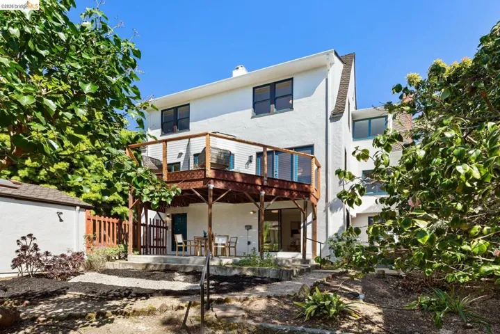 Rear view of property with stucco siding, a chimney, and a wooden deck