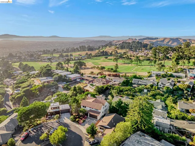 Aerial perspective of suburban area with a mountainous background and a local golf course