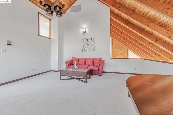 Carpeted living area featuring wooden ceiling and baseboards