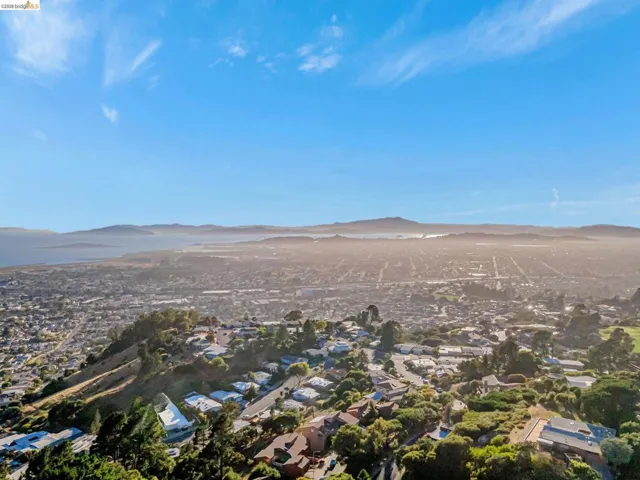 Aerial view of property and surrounding area featuring a mountainous background and nearby suburban area