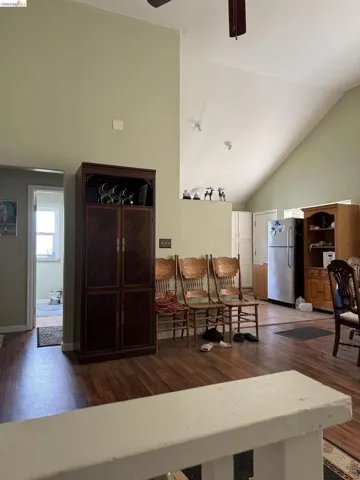 Living room featuring dark wood-style flooring, a ceiling fan, and lofted ceiling