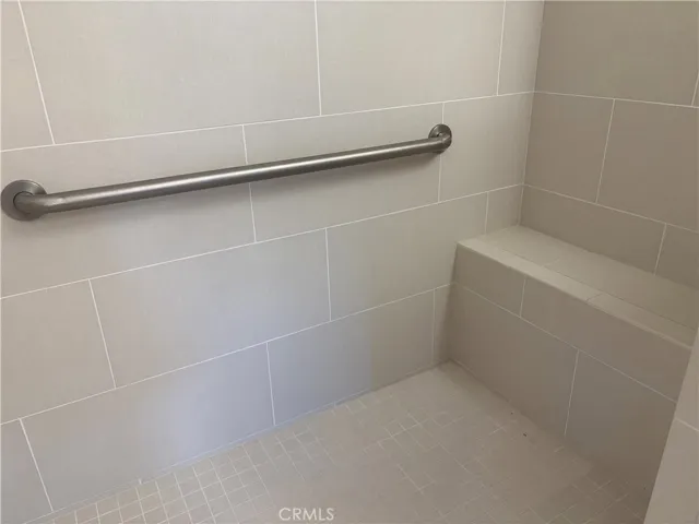 Walk-in shower with built-in shower seat and a handicap grab bar.
