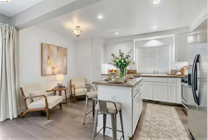 Kitchen with dark stone counters, stainless steel appliances, white cabinetry, a kitchen breakfast bar, and a center island