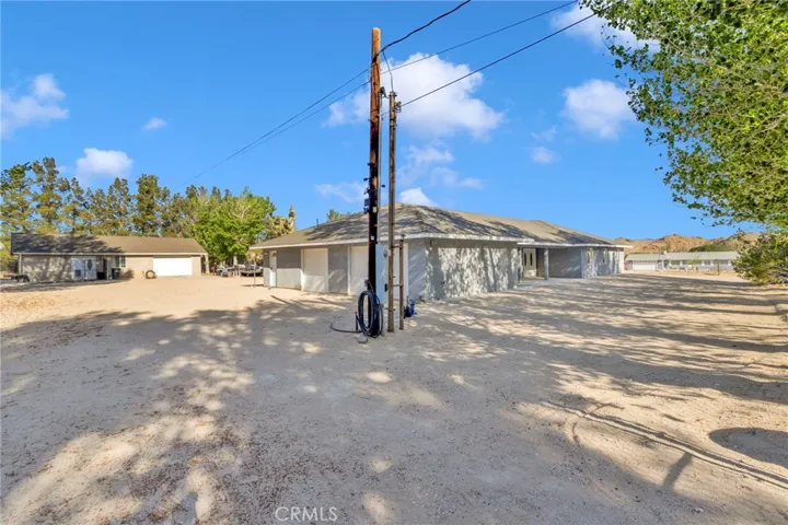 Beautiful 2+ acre compound showcasing the newer construction 5-bedroom main home, detached studio, mature trees, green lawn, and spacious circular driveway.