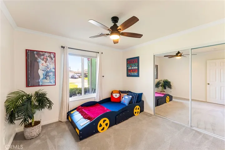 2nd Downstairs Bedroom with Mirrored Closet, Crown Molding, and Ceiling Fan