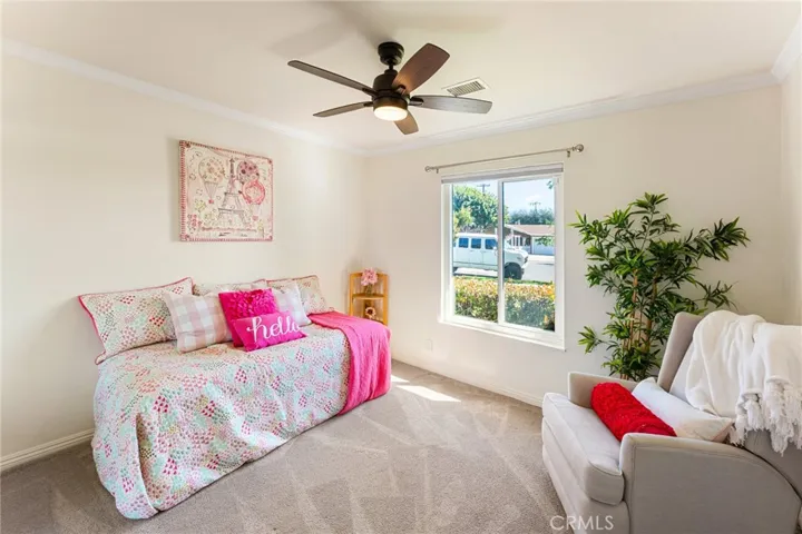3rd Downstairs Bedroom with Mirrored Closet, Crown Molding, and a Ceiling Light Fan