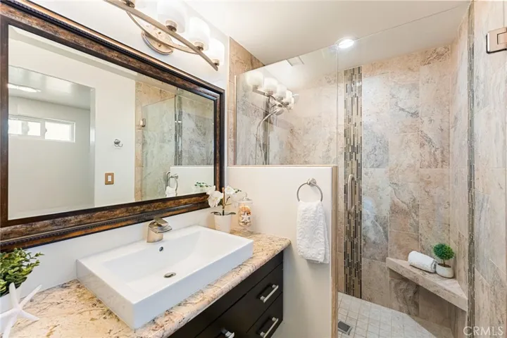 Primary Bath with Granite Counters, Contemporary Self-Closing Vanity Cabinets, Vessel Sink, Designer Mirror and Floating Shelves, Oversized Walk-In Shower with Designer Tile Surround with Glass Mosaic Tile Inlay and Frameless Glass Enclosure. Privacy Toilet and Linen Cabinets Around the Corner