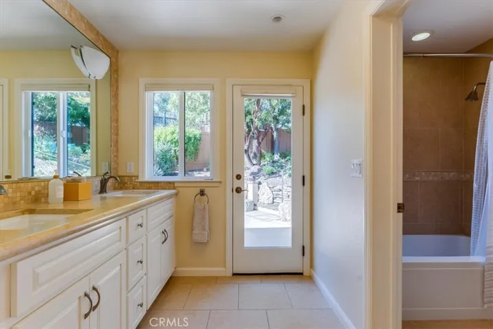 Hall bathroom with dual sinks and exterior access.