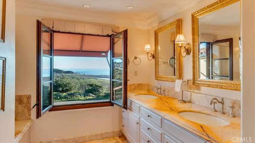 Primary bathroom has ocean views and marble floors and countertops.