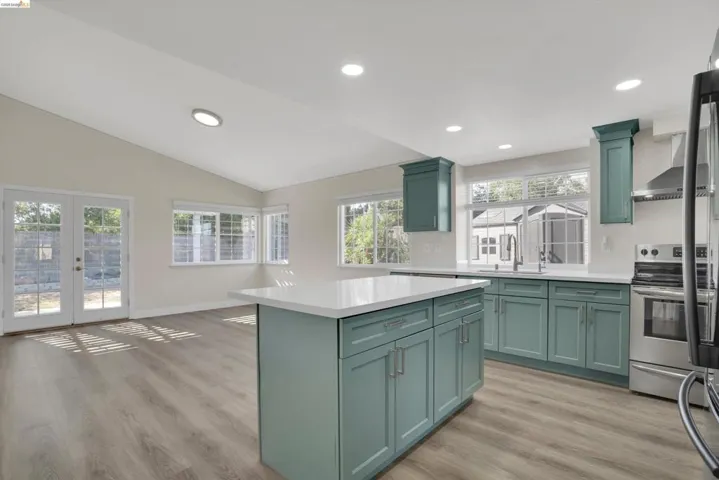Kitchen with green cabinetry, french doors, light wood-style floors, stainless steel appliances, and a center island