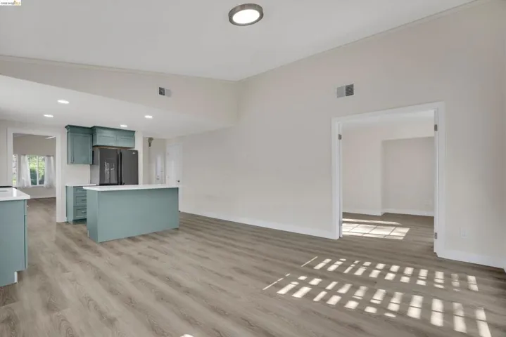 Unfurnished living room featuring light wood-style floors, lofted ceiling, recessed lighting, and ornamental molding