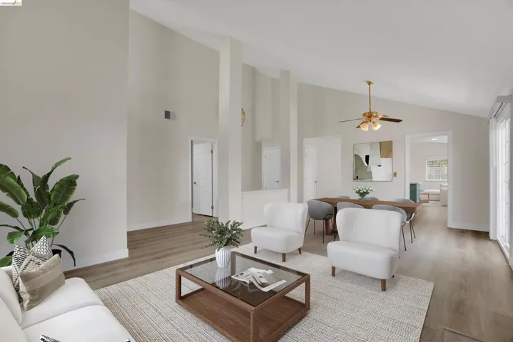 Living area with light wood-style floors, ceiling fan, and vaulted ceiling