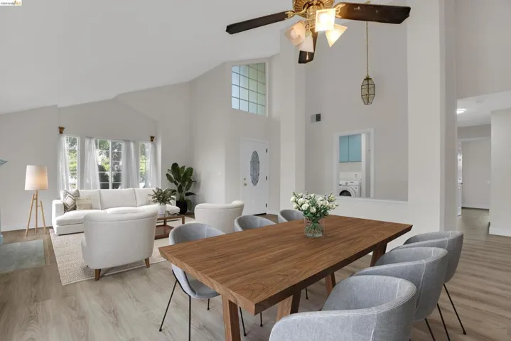 Dining room featuring light wood-style flooring, washer / clothes dryer, a ceiling fan, and lofted ceiling