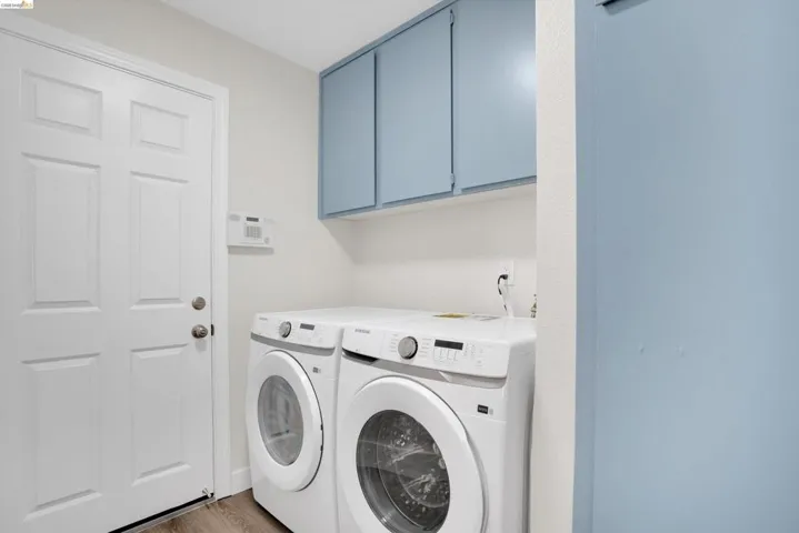 Laundry room with washing machine and clothes dryer, light wood-style flooring, and cabinet space