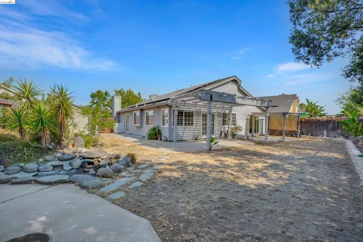 Rear view of house featuring a fenced backyard, a pergola, roof mounted solar panels, a patio area, and stucco siding